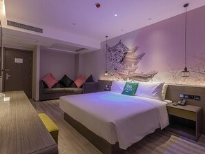 A modern hotel room with a large bed, a sofa, a desk, and a wall-mounted TV. - ibis Styles Wuhan Optics Valley Square Hotel (Wuhan)