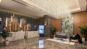 A modern lobby with a reception desk, a peacock mural, a sofa, and a chandelier. - ibis Styles Wuhan Optics Valley Square Hotel (Wuhan)