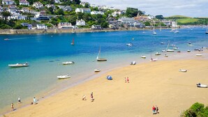 A coastal town with a sandy beach, boats, and houses on a hillside. - Harbour Hotel Salcombe (Salcombe)