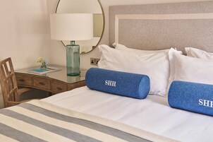 Una habitación de hotel con una cama, un escritorio, una lámpara y un espejo.