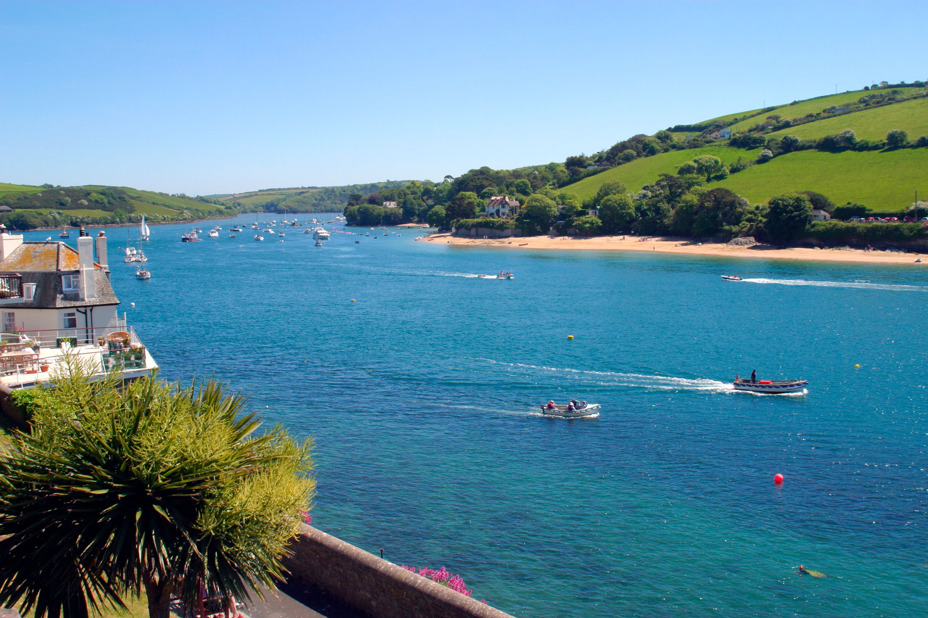 Una cittadina costiera con un porto turistico, barche e una spiaggia sabbiosa.