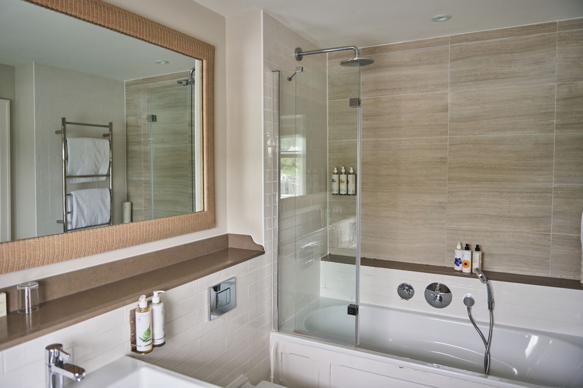 A modern bathroom with a glass-enclosed shower, a large mirror, and a bathtub.