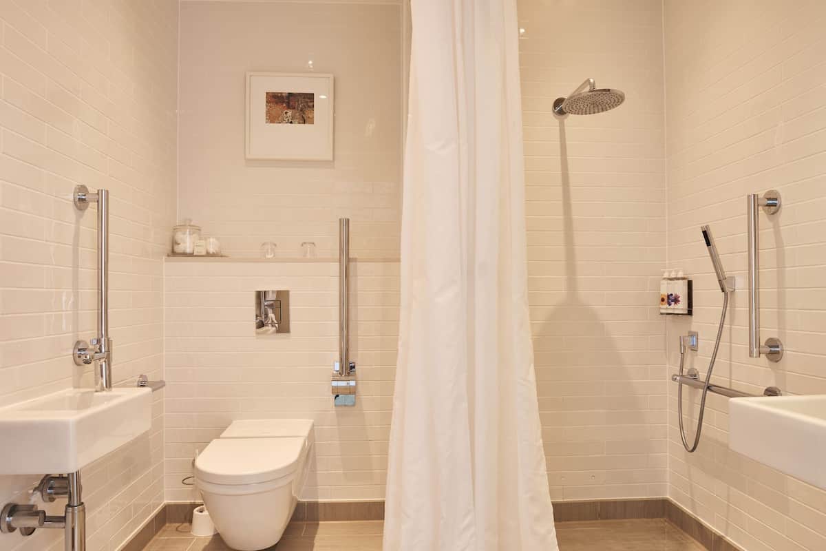 A modern bathroom with a toilet, sink, shower, and a framed picture on the wall.