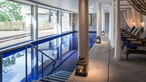 A pool area with a glass barrier, steps leading down to the pool, and lounge chairs with cushions. - Harbour Hotel Salcombe (Salcombe)