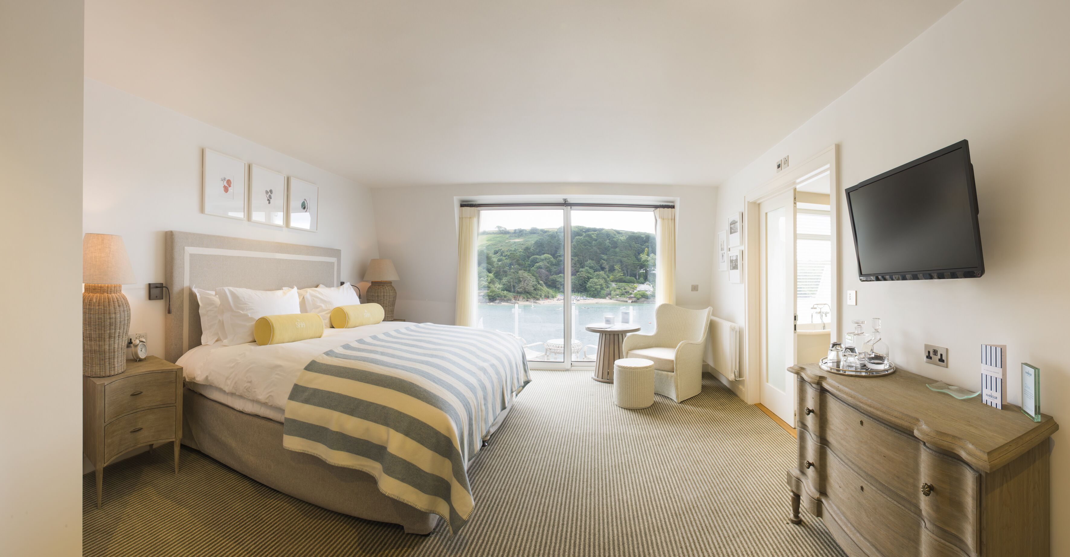 A hotel bedroom with a large bed, a TV, a desk, and a view of the outdoors.