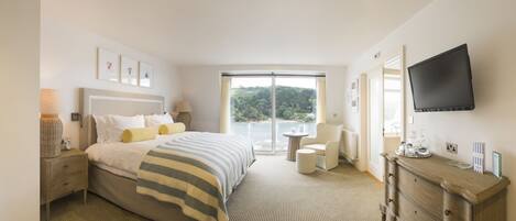 A hotel bedroom with a large bed, a TV, a desk, and a view of the outdoors.