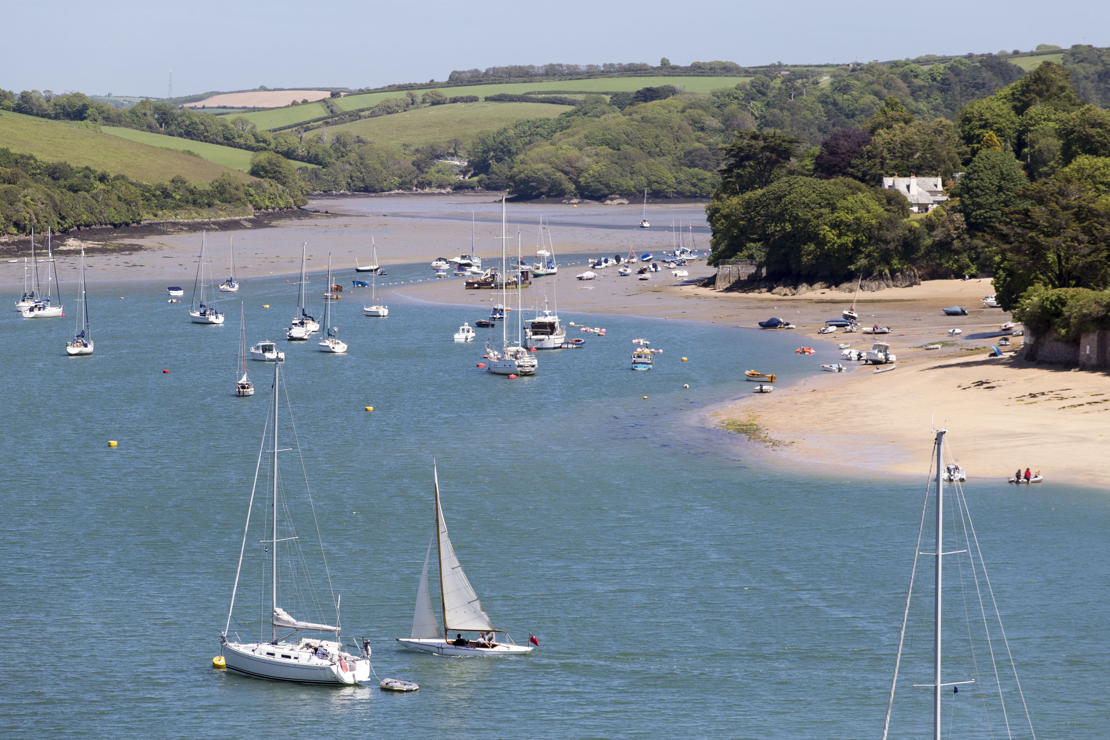A coastal area with numerous boats on the water and a sandy beach.