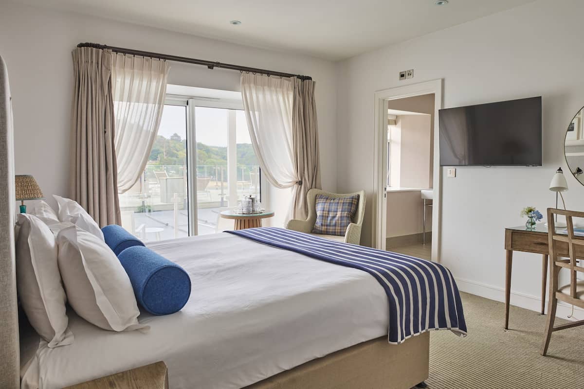 A hotel room with a large bed, a TV, a desk, and a chair.