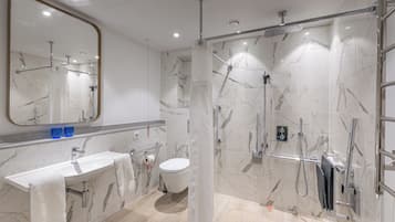 A modern bathroom with a marble sink, toilet, and shower area.
