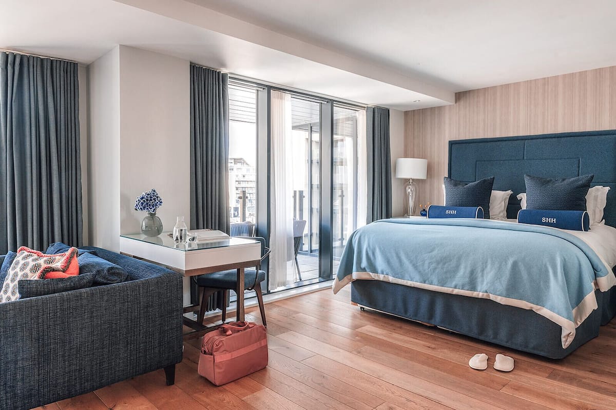 A modern hotel room with a large bed, a desk, and a seating area.