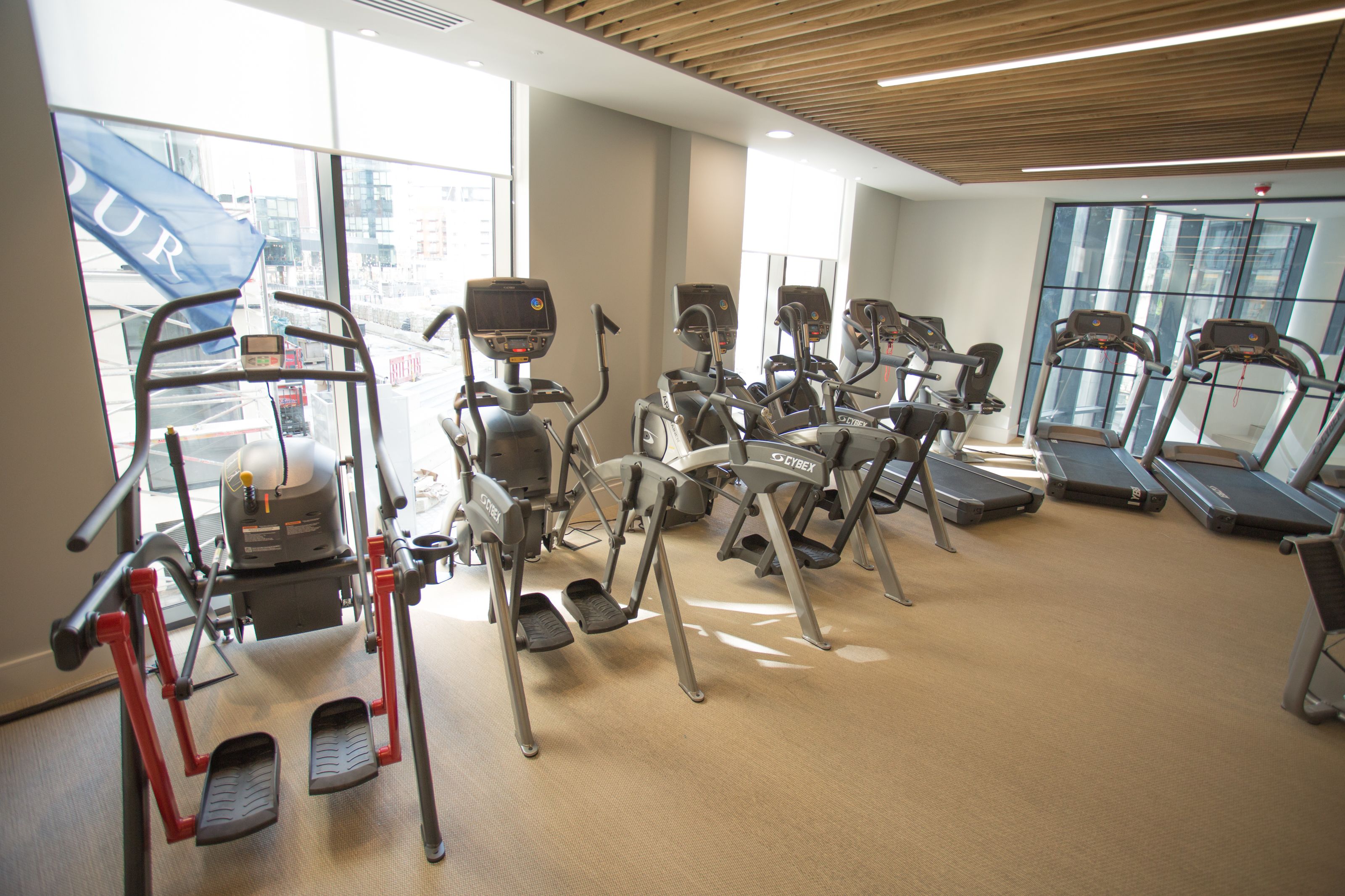 A gym with various exercise equipment, large windows, and a view of the city.