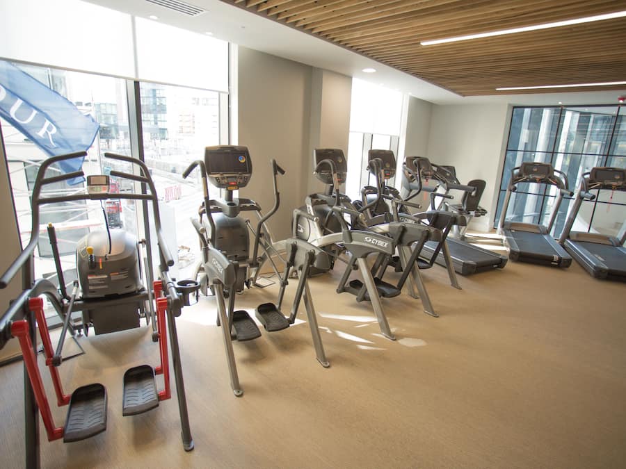 A gym with various exercise equipment, large windows, and a view of the city.