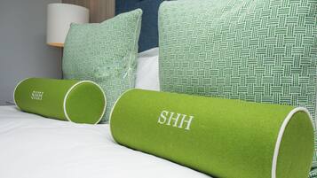 A bed with green cylindrical pillows and a white pillow with a green pattern.