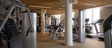 A gym with various exercise equipment, including a treadmill, elliptical, and weight machines.