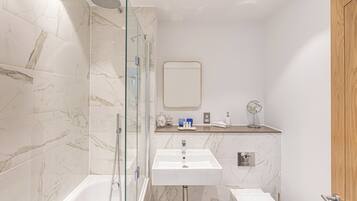 Een moderne badkamer met een douchecabine van glas, een wit wastafelmeubel en een houten deur.