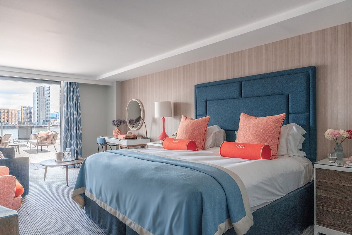 A modern hotel room with a large bed, a desk, and a view of the city.