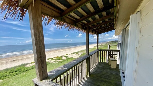 Una terraza de madera con barandilla que da a una playa.