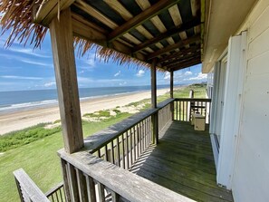 A wooden deck with a railing overlooking a beach. - Love Shack 2 Bedroom Home by RedAwning (Port Bolivar)