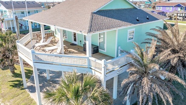 A two-story house with a balcony, a deck, and a small porch area. - Parrot Head 3 Bedroom Home by RedAwning (Port Bolivar)
