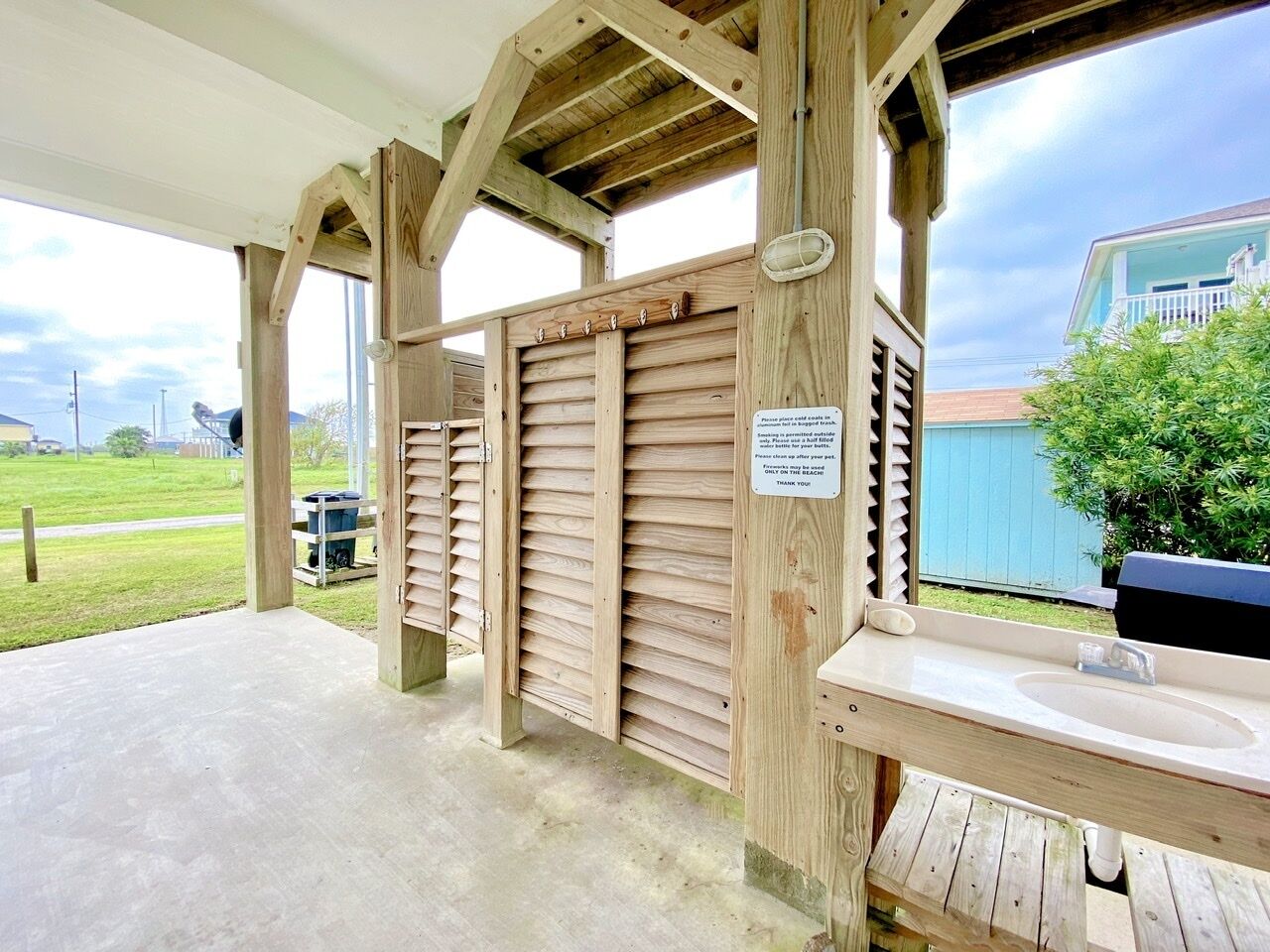 Un baño exterior de madera con banco y lavamanos.