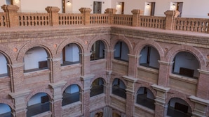 A multi-level atrium with arched windows and brick walls. - Parador de Lleida (Lleida)