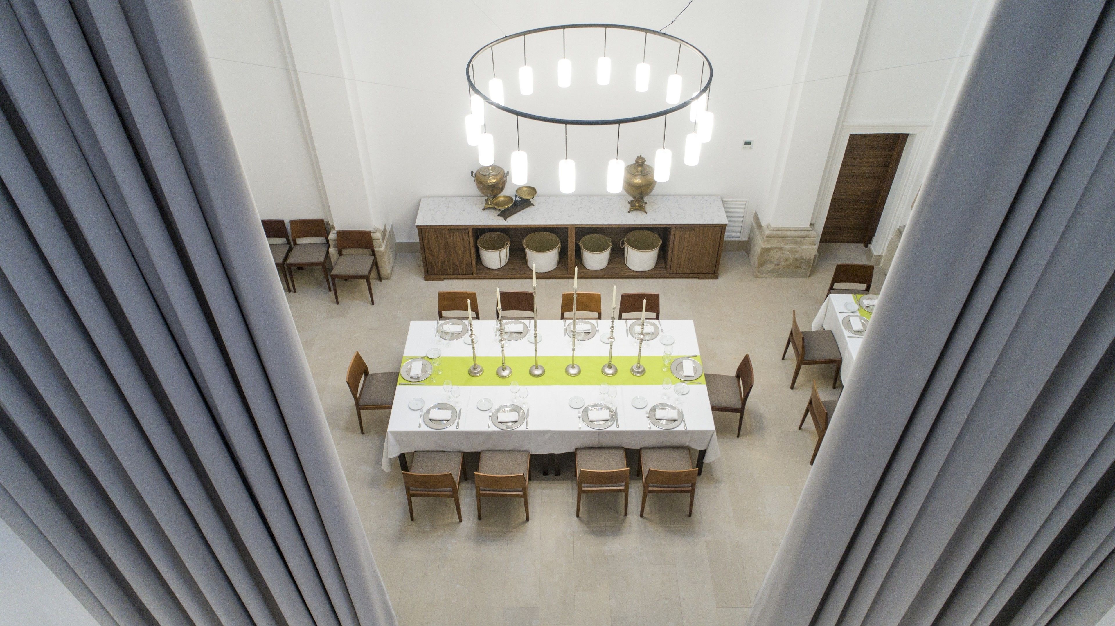 Ein Essbereich mit einem langen Tisch, der für mehrere Gäste gedeckt ist, umgeben von Stühlen.