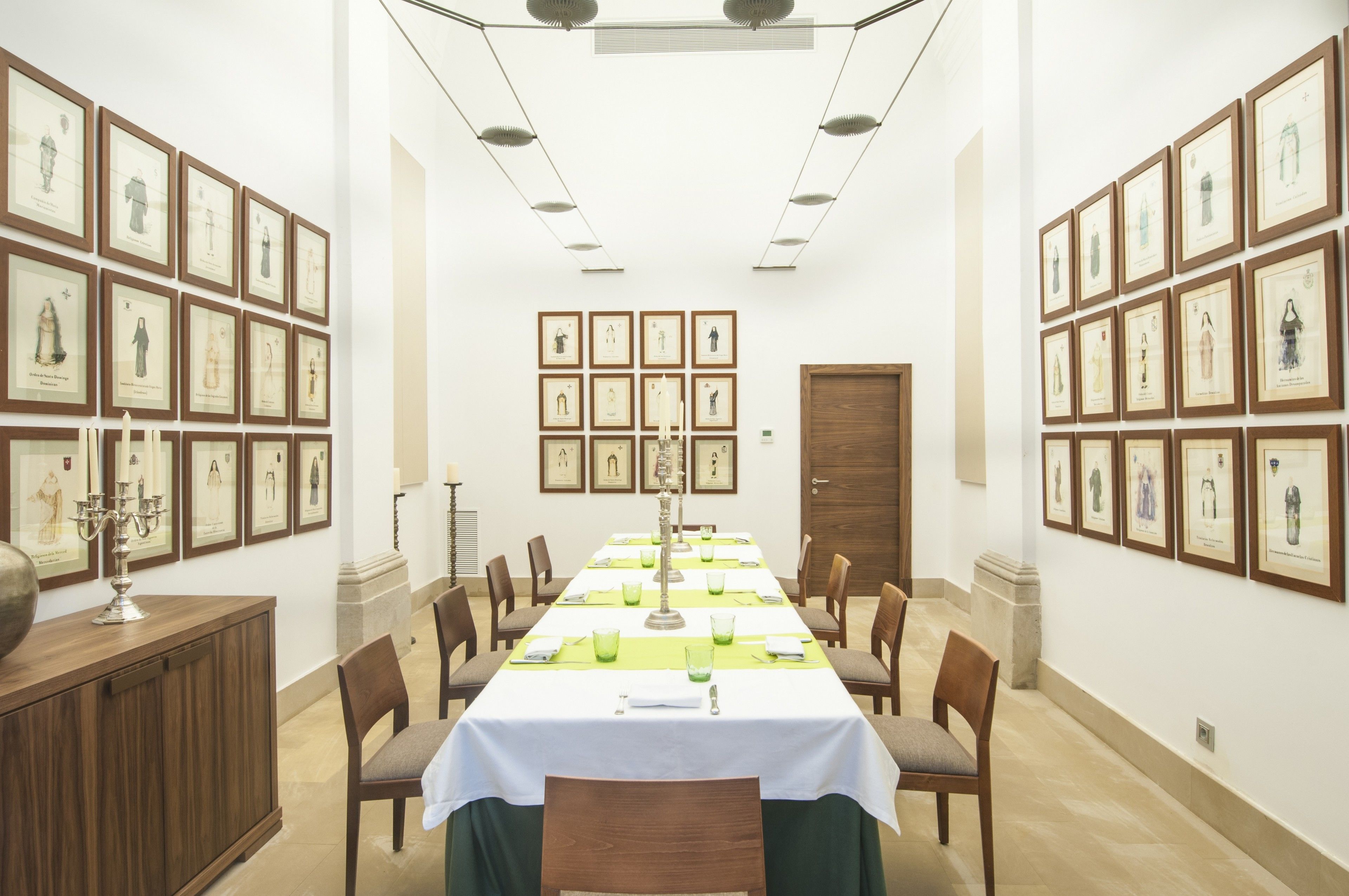 Une salle de conférence avec une longue table, des chaises, des œuvres d’art encadrées accrochées aux murs et un buffet en bois.