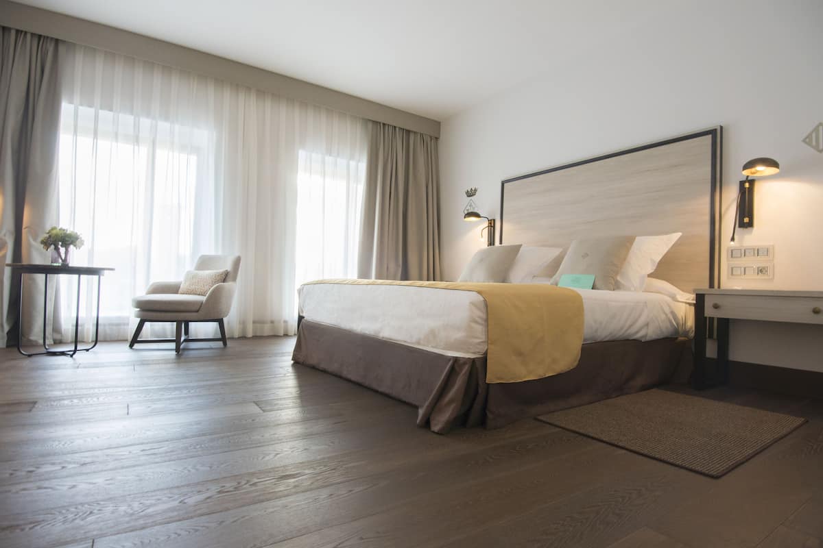 Una habitación de hotel moderna con una cama grande, una mesita de noche, una silla y un escritorio.