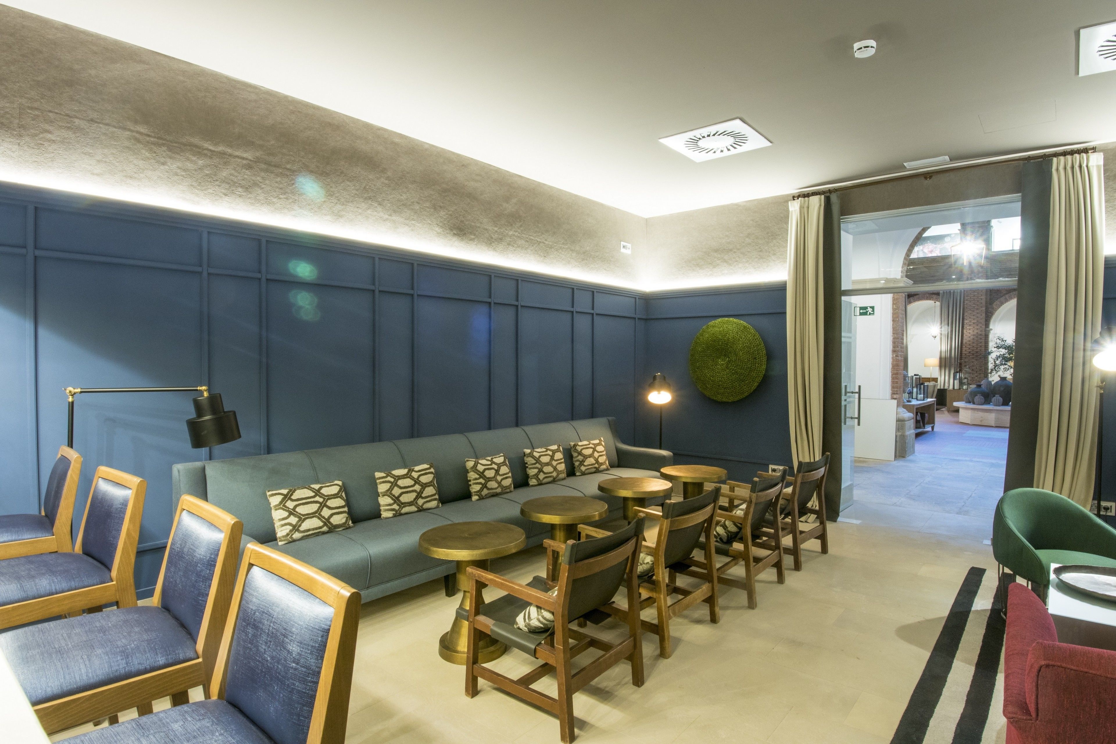 Een moderne zithoek met een bank, stoelen en ronde tafels.