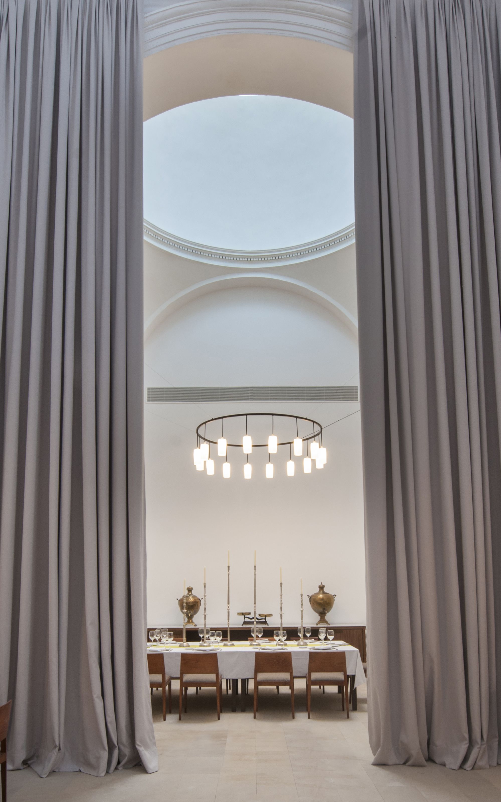 A dining area with a high ceiling, a chandelier, and a table set for a meal.