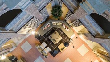 Een ruime atrium met een centraal zitgedeelte, een potplant en een trap.