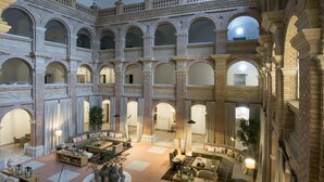 A spacious atrium with multiple arches, a central seating area, and a high ceiling. - Parador de Lleida (Lleida)