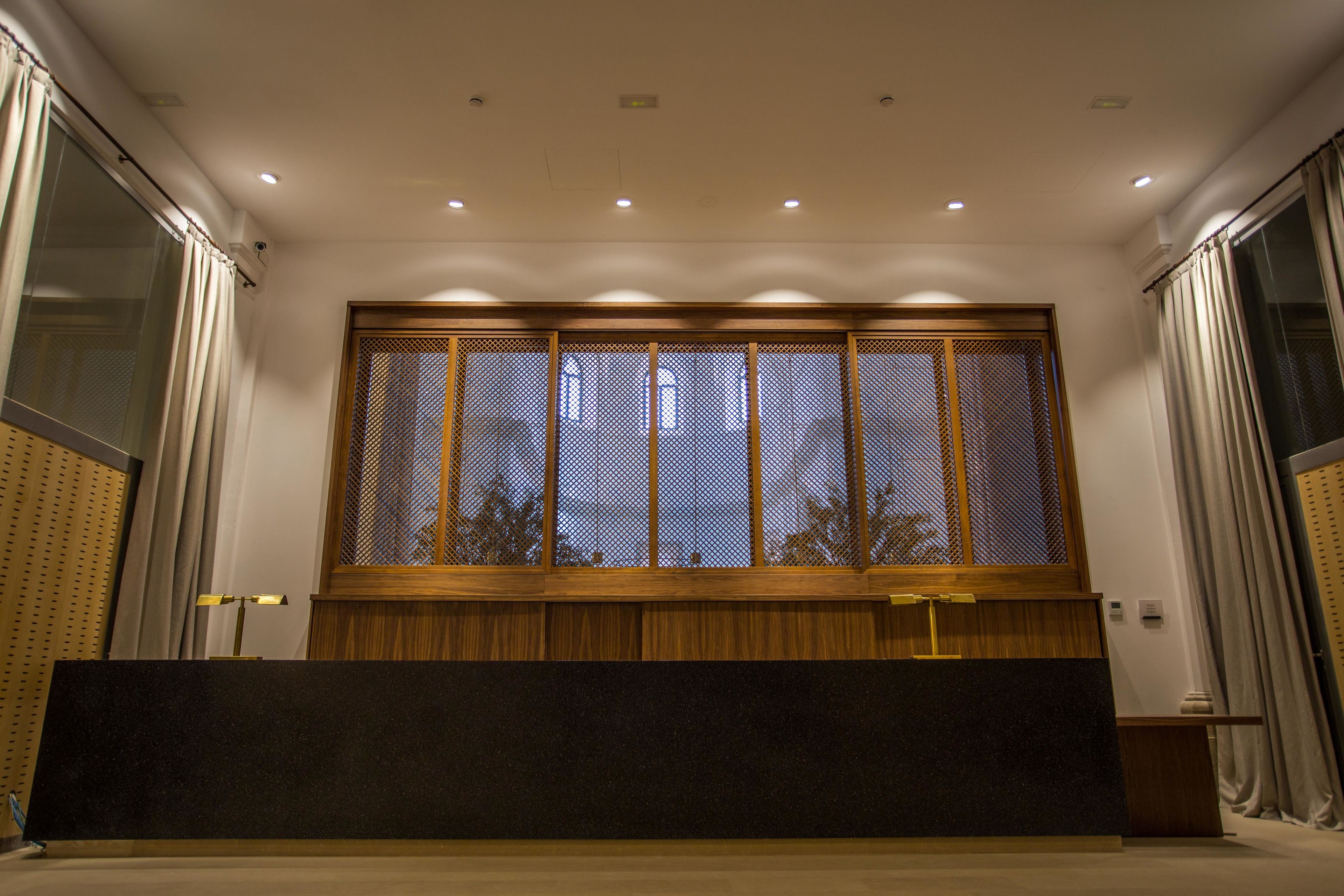 A room with a large window, a wooden panel, and a black counter.