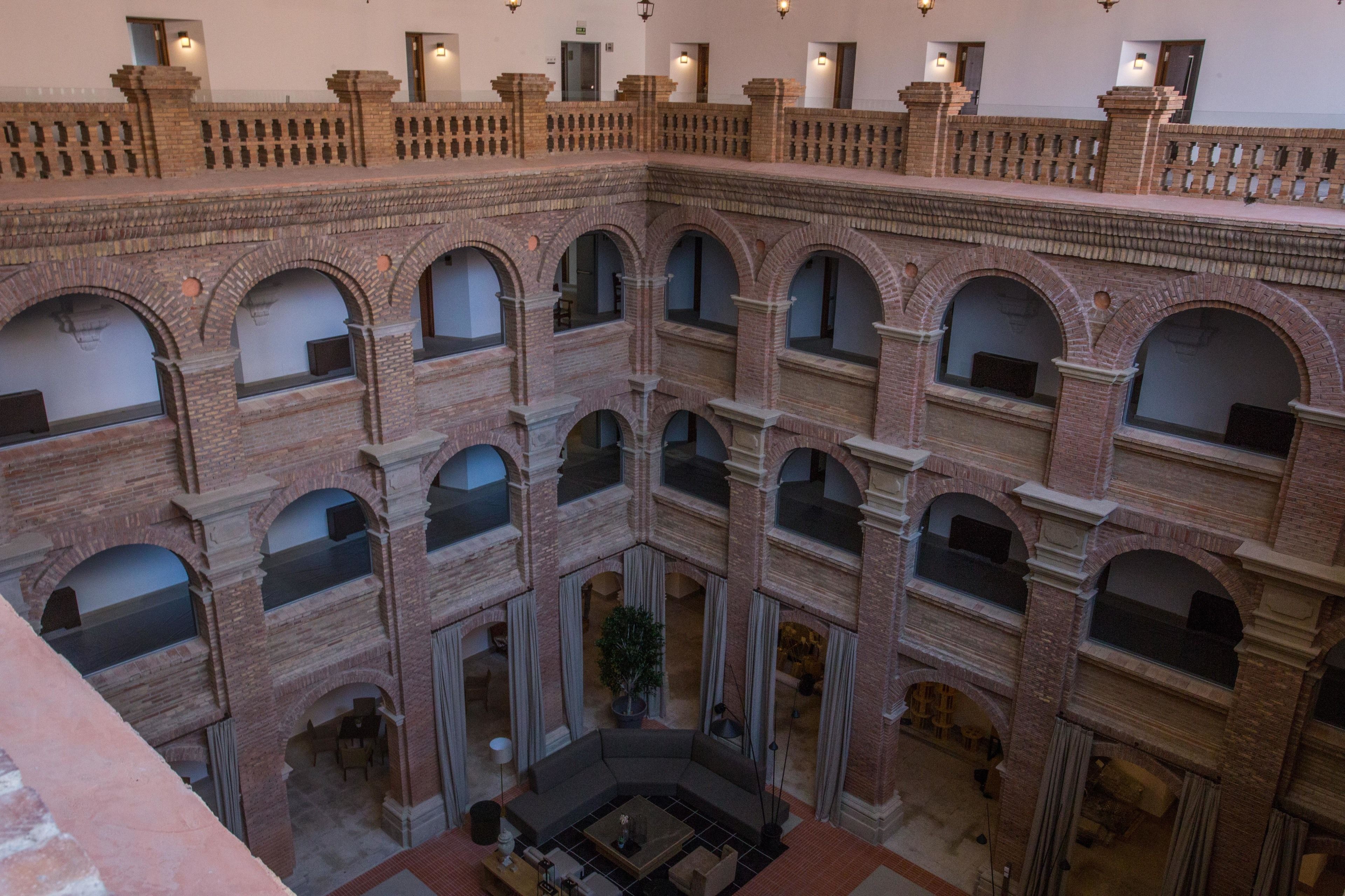 Ein mehrgeschossiges Atrium mit Backsteingestaltung, mehreren Balkonen und einer zentralen Sitzgruppe.