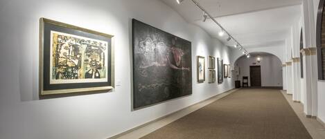 An art gallery with framed artworks on white walls and a carpeted floor.