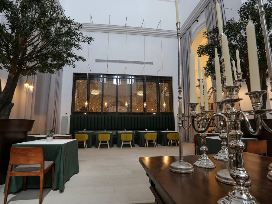 Un comedor con mesas y sillas, un árbol grande y un candelabro decorativo.