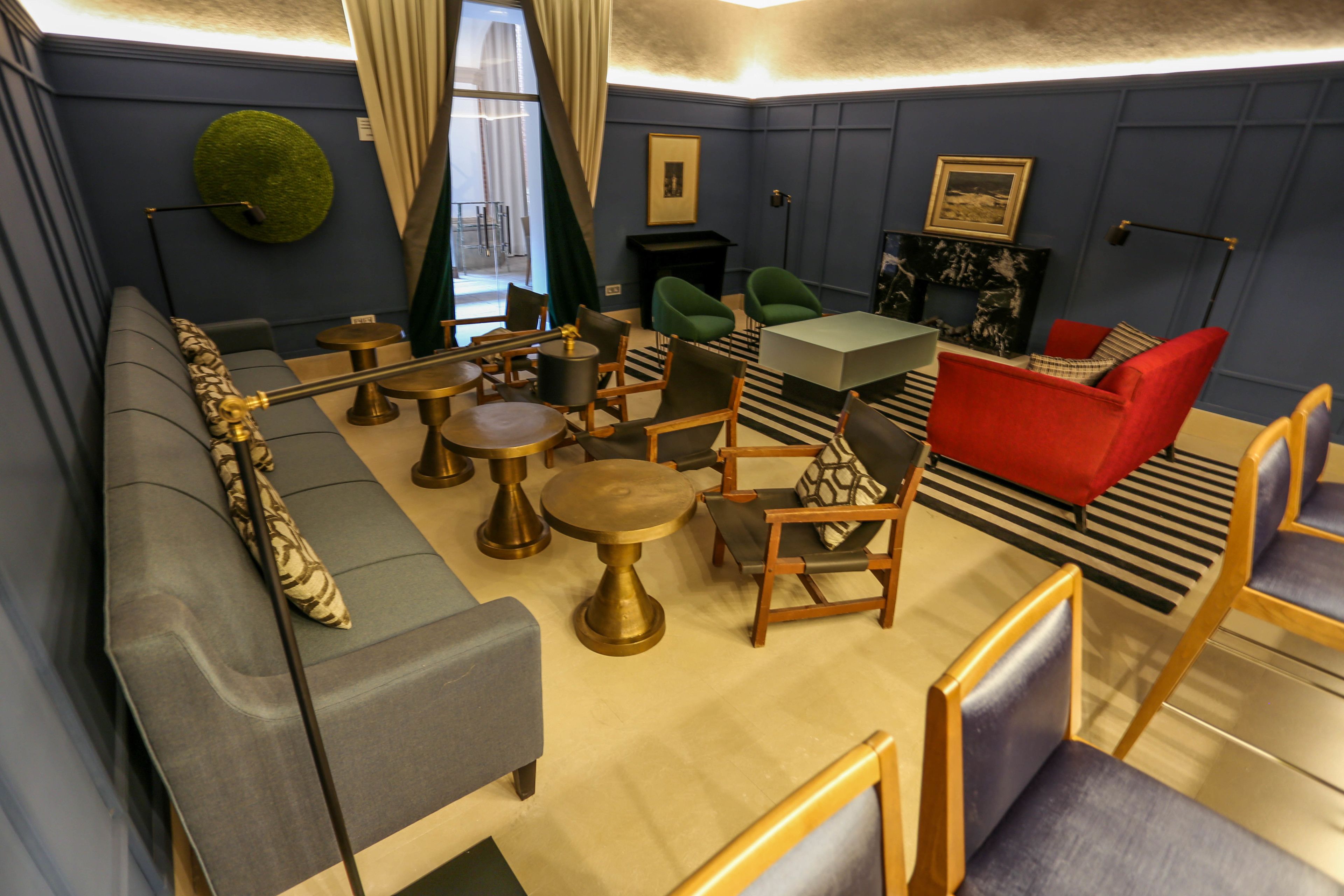 Una sala de estar moderna con un sofá gris, sillas verdes y rojas, una mesa de centro y una chimenea.
