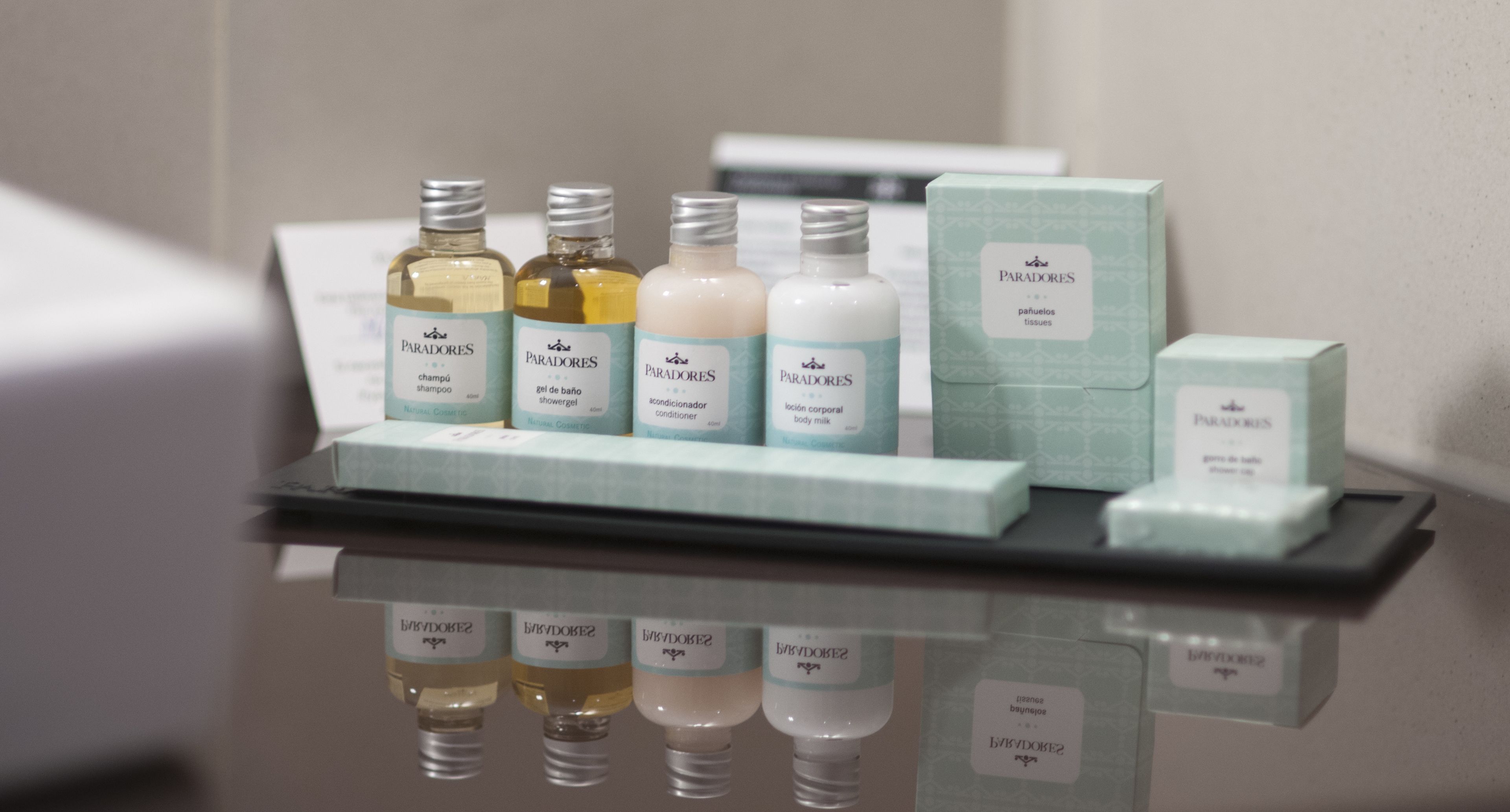 A display of Paradores hotel toiletries including shampoo, shower gel, conditioner, body milk, and tissues.