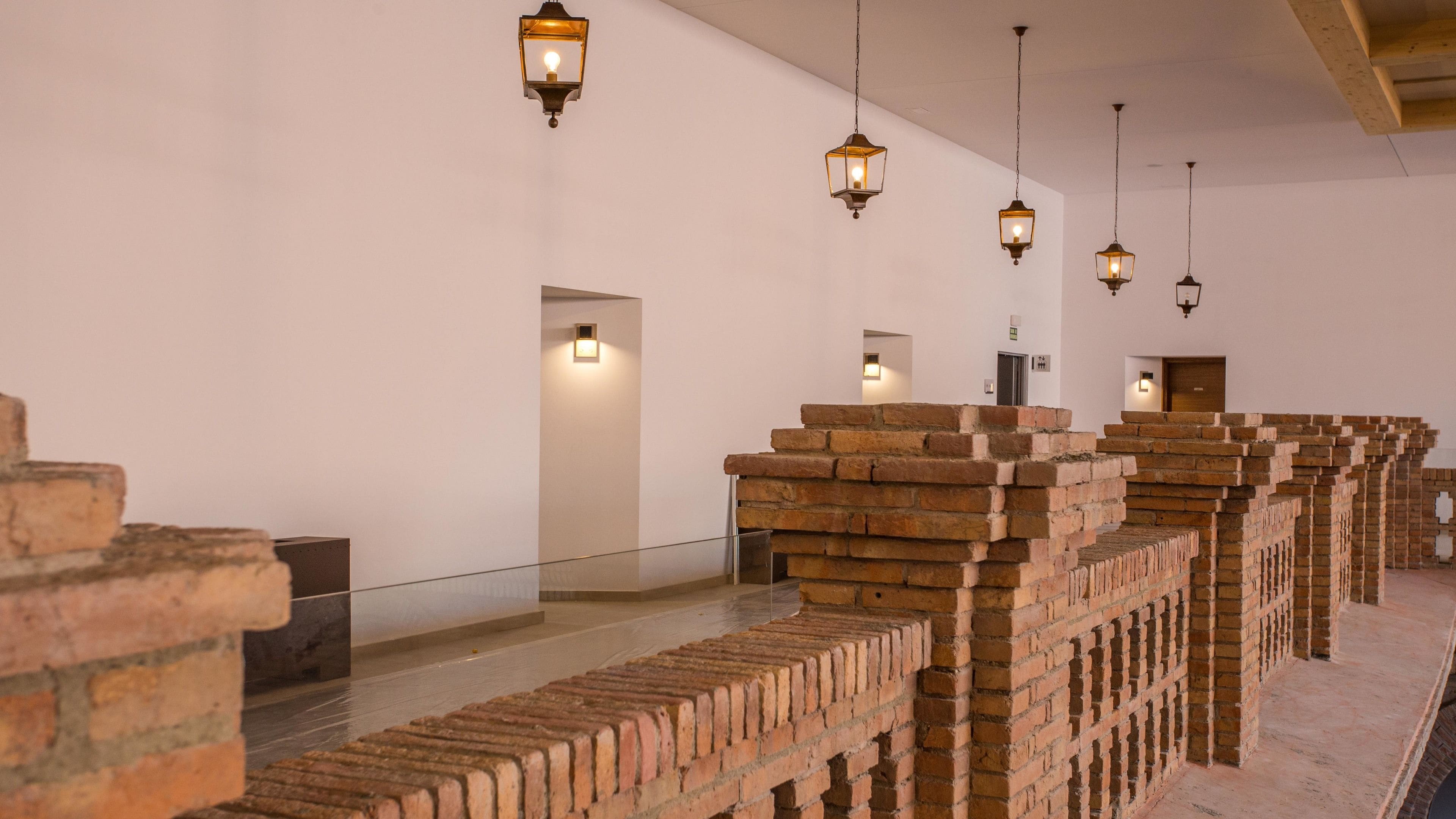 Un pasillo con paredes de ladrillo y lámparas colgantes de estilo farol.