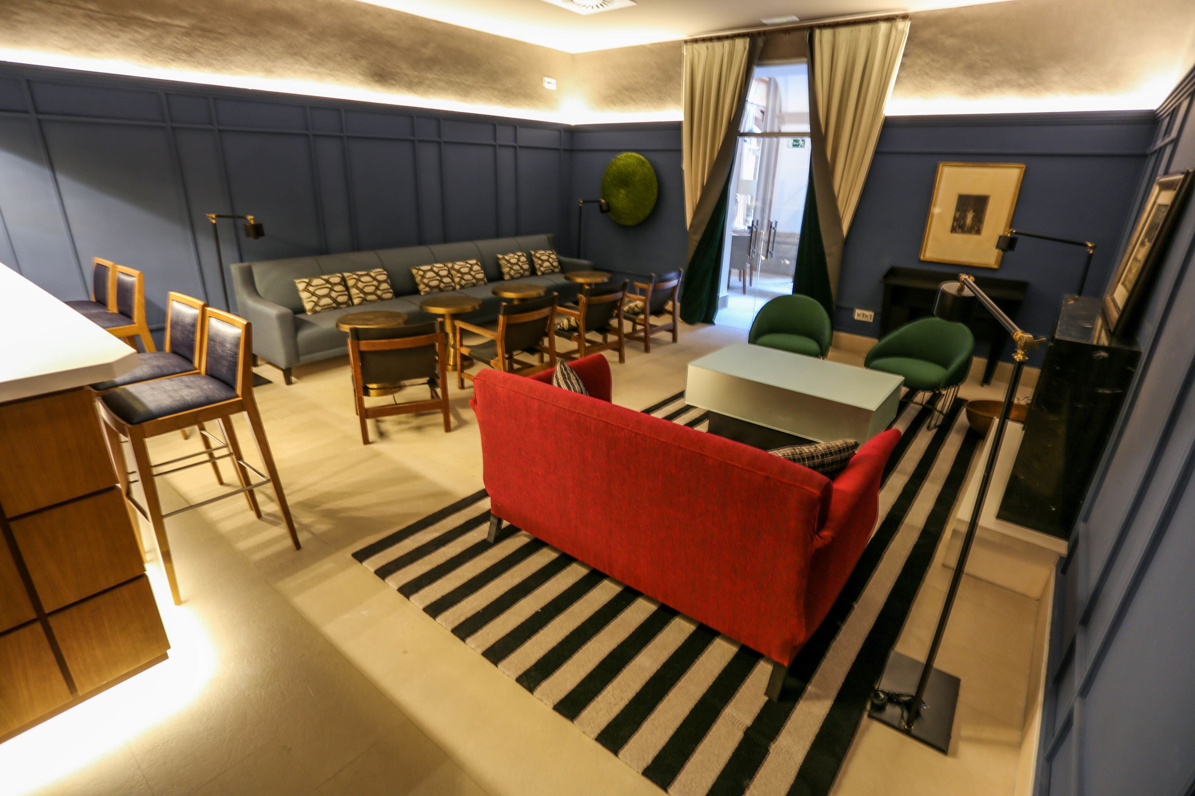 A modern living room with a sofa, chairs, a dining table, and a red couch.