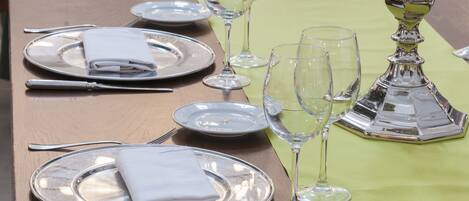 Una mesa dispuesta con cubiertos, platos y copas de vino, con mantel verde y un candelabro de plata.