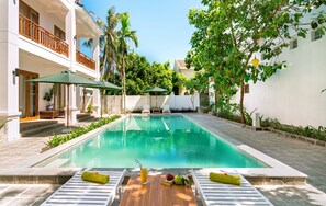 Una piscina al aire libre, sillones reclinables de piscina