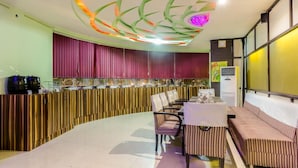 Een modern restaurant met een gebogen toonbank, gestreepte zitplaatsen en een decoratieve plafondlamp.