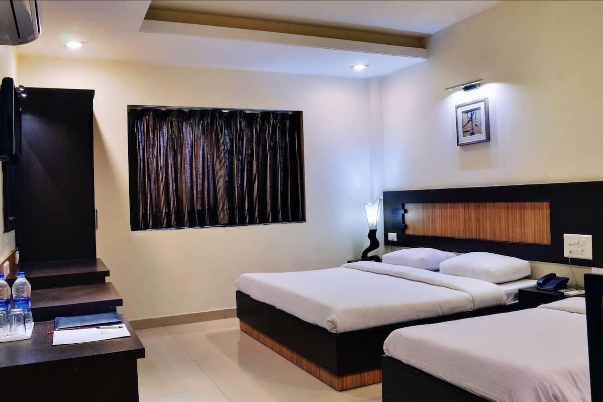 A hotel room with a bed, bedside table, and a window with curtains.