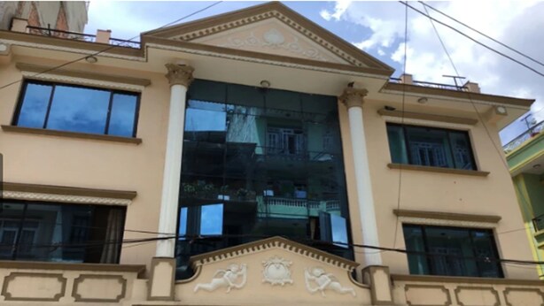 A building with a central glass facade, columns, and decorative elements. - Namaste Home (Kathmandu)