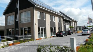 Un hôtel moderne doté d’un toit plat, de grandes fenêtres et d’un chemin piétonnier pavé.