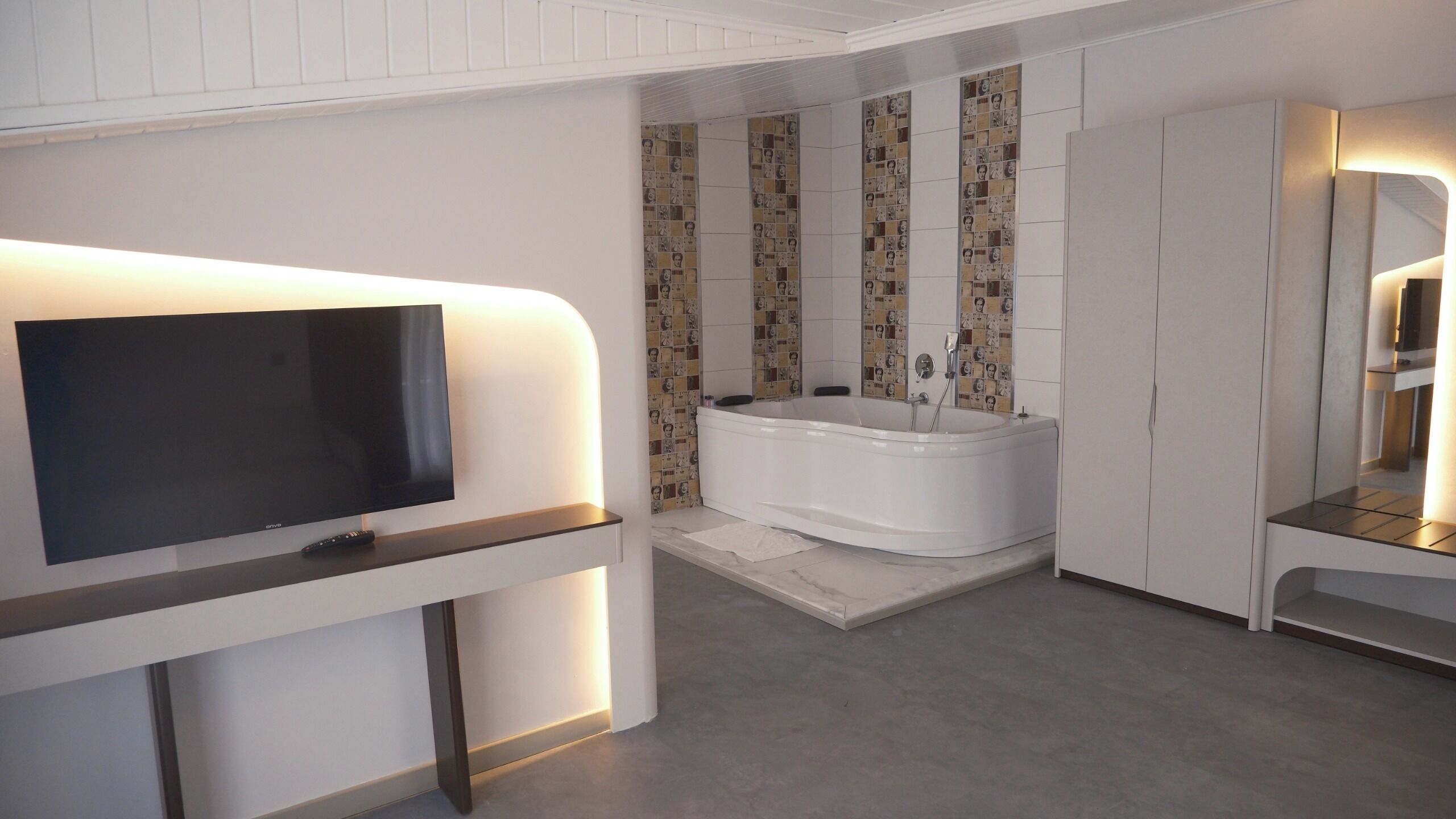 Un baño moderno con televisor, bañera y tocador con espejo.