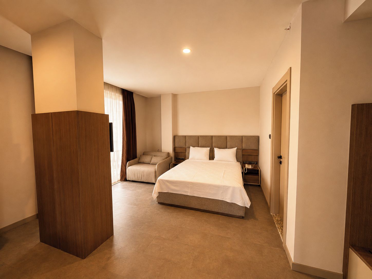 Una habitación de hotel con una cama grande, una zona de estar y un armario.