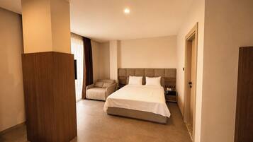 Una habitación de hotel con una cama grande, una zona de estar y un armario.