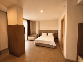 Una habitación de hotel con una cama grande, una zona de estar y un armario.